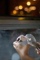 Close up hand of a person scooping ice cream in to a paper bowl with blurred background photo