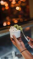 Close up hand of a person scooping ice cream in to a paper bowl with blurred background photo