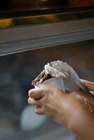 Close up hand of a person scooping ice cream in to a paper bowl with blurred background photo