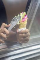 Close up hand of a person scooping ice cream in to a cone with blurred background photo