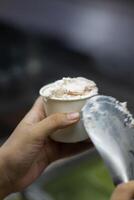 Close up hand of a person scooping ice cream in to a paper bowl with blurred background photo