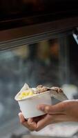 Close up hand of a person scooping ice cream in to a paper bowl with blurred background photo