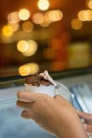 Close up hand of a person scooping ice cream in to a paper bowl with blurred background photo