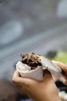 Close up hand of a person scooping ice cream in to a paper bowl with blurred background photo