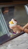 Close up hand of a person scooping ice cream in to a paper bowl with blurred background photo