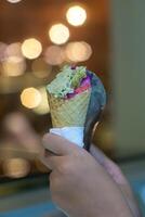 Close up hand of a person scooping ice cream in to a cone with blurred background photo