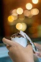 Close up hand of a person scooping ice cream in to a paper bowl with blurred background photo