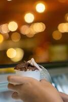 Close up hand of a person scooping ice cream in to a paper bowl with blurred background photo