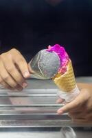 Close up hand of a person scooping ice cream in to a cone with blurred background photo