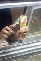 Close up hand of a person scooping ice cream in to a cone with blurred background photo