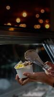 Close up hand of a person scooping ice cream in to a paper bowl with blurred background photo