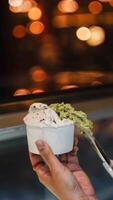 Close up hand of a person scooping ice cream in to a paper bowl with blurred background photo