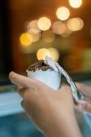 Close up hand of a person scooping ice cream in to a paper bowl with blurred background photo