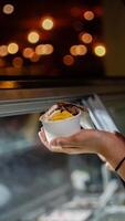 Close up hand of a person scooping ice cream in to a paper bowl with blurred background photo