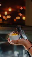 Close up hand of a person scooping ice cream in to a paper bowl with blurred background photo