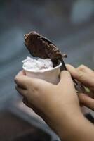 Close up hand of a person scooping ice cream in to a paper bowl with blurred background photo