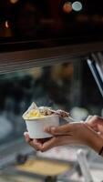 Close up hand of a person scooping ice cream in to a paper bowl with blurred background photo
