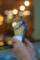 Close up hand of a person scooping ice cream in to a cone with blurred background photo