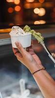 Close up hand of a person scooping ice cream in to a paper bowl with blurred background photo