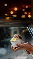 Close up hand of a person scooping ice cream in to a paper bowl with blurred background photo