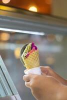 Close up hand of a person scooping ice cream in to a cone with blurred background photo