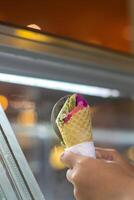 Close up hand of a person scooping ice cream in to a cone with blurred background photo