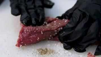 Salt beef tenderloin Chef cooks beef steak, sprinkling with salt on a background of professional kitchen, slow motion. video