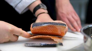 Sushi Chef Slices fresh Salmon on the sushi bar. Chef cutting salmon fillet at professional kitchen. Closeup chef hands slicing fresh fish slice in slow motion. Professional man cutting red fish video