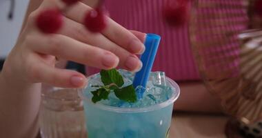 Blue drink with mint cool drink with mint and ice in a glass with a blue straw on a lawn. rotating glass with lime lemonade and mint leaves and splashes from a falling ice cube video