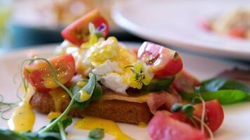 Egg benedict with hollandaise sauce and smoked salmon on toast Eggs Benedict with bread and tomato on a plate with becon morning sandwich video