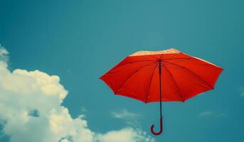 Bright Red Umbrella Floating in Clear Blue Sky With Clouds photo