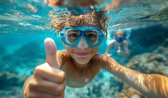 Boy Snorkeling With Goggles Giving Thumbs Up in Clear Water. A young boy enjoying snorkeling photo