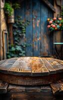A wooden table with a round top sits in front of a blue door. The door is open and has vines growing on it. photo