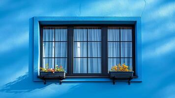 A window with three panes of glass and a blue wall behind it. The window is filled with potted plants and flowers photo