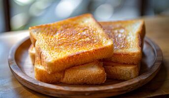 A plate of toasted bread with a wooden plate. The bread is toasted and has a golden brown color photo