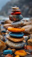 A stack of rocks with a blue and orange rock in the middle. The rocks are arranged in a pyramid shape photo