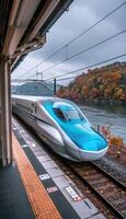 A blue and white train is smoothly going down the tracks swiftly photo