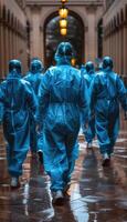 People in protective suits are walking down a wet street photo