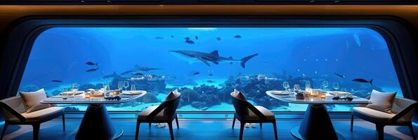 Two tables and chairs in front of a large aquarium with sharks photo