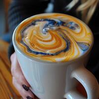 A woman is holding a cappuccino cup with a lovely blue swirl photo