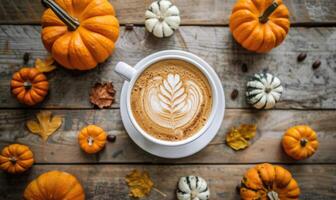 A cup of coffee with a pumpkin spice latte, surrounded by small pumpkins photo