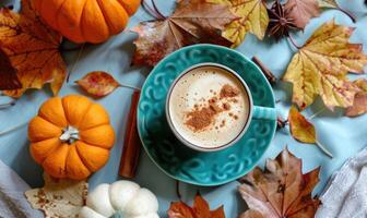 A warm pumpkin chai latte, topped with a sprinkle of cinnamon surrounded by small pumpkins and vibrant autumn leaves photo