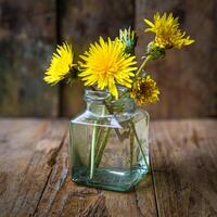 Small bouquet of dandelions in a glass vase on a wooden background. Minimalism. photo