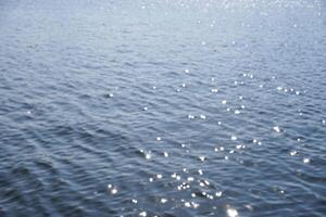 Blur and defocused effect on calm blue shiny sea water texture isolated on full frame horizontal background. photo