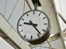 Big round analog clock hanging on indoor building ceiling isolated on horizontal train station interior environment background. photo