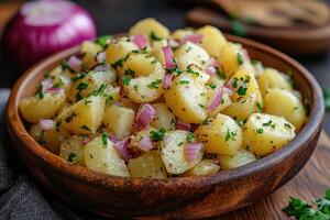 Delicious potato salad with red onions and mustard dressing in wooden bowl photo