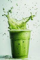 Green smoothie splashing out of plastic cup photo