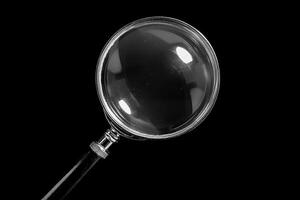 Magnifying glass on black background exploring the unknown photo