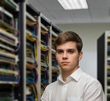 Data Centre Operator. A young man standing in data center and looking at camera. photo