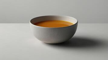 A bowl of Fiskesuppe on a white table against a gray background photo